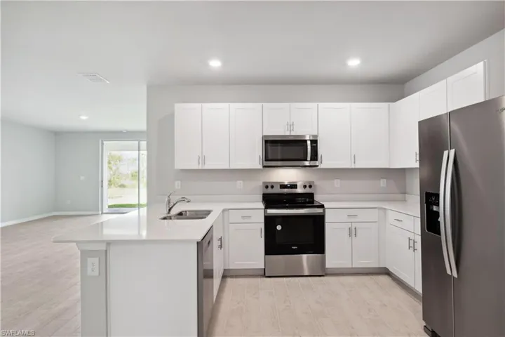 Kitchen with light hardwood / wood-style floors, kitchen peninsula, and stainless steel appliances