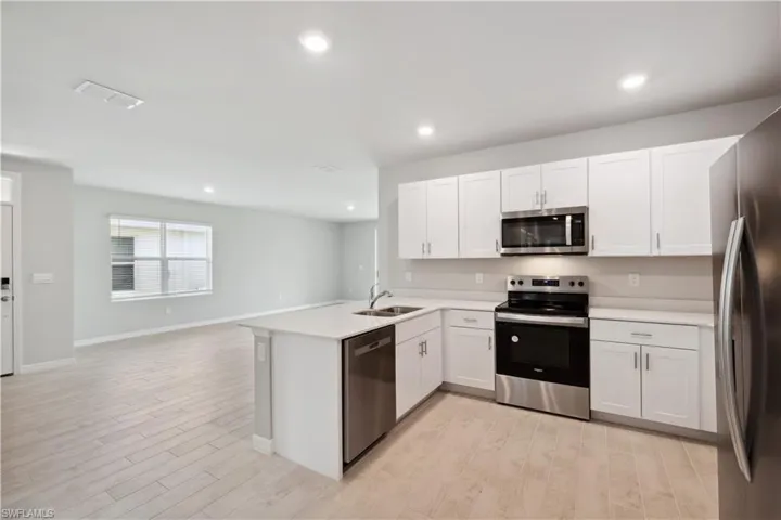 Kitchen featuring white cabinets, stainless steel appliances, light hardwood / wood-style flooring, and kitchen peninsula