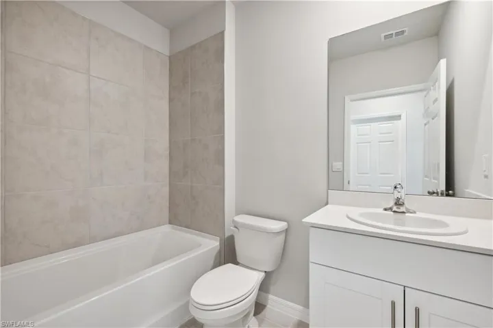 Full bathroom with vanity, tiled shower / bath, and toilet