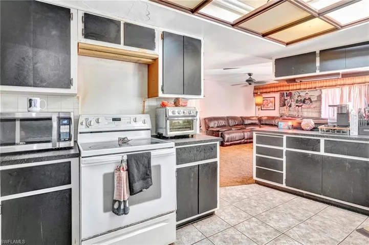 Kitchen with electric range, ceiling fan, and light tile floors