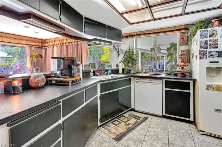 Kitchen with sink, white appliances, and light tile floors