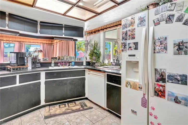 Kitchen with sink, white appliances, and light tile floors