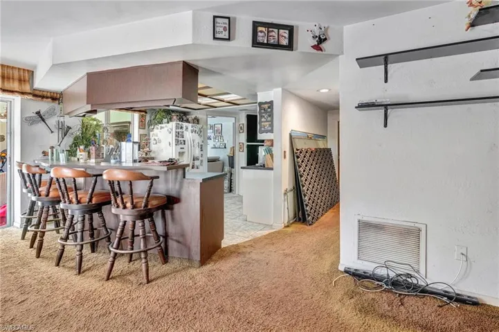 Kitchen featuring light colored carpet, kitchen peninsula, a kitchen bar, and fridge