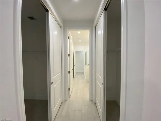 Hallway featuring light wood-finish flooring, recessed lighting, and white panel doors