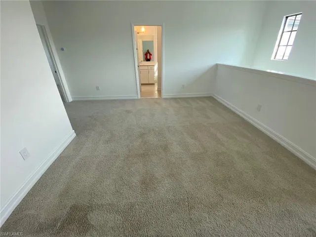 Carpeted open area with white walls and baseboards