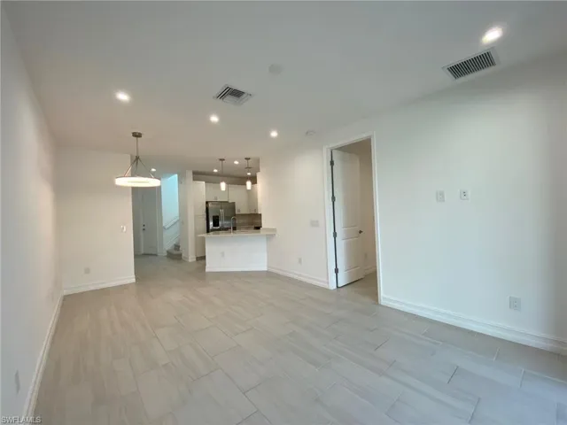 Open-concept living area featuring light-toned tile flooring, recessed lighting, and a contemporary pendant fixture