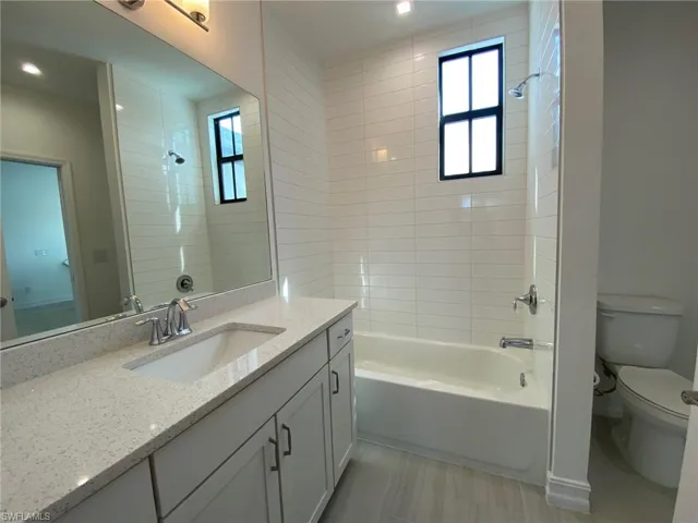 Bathroom featuring a single vanity with a quartz-finish countertop, undermount sink, and chrome fixtures