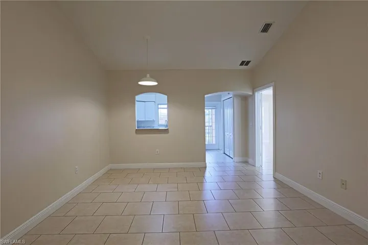 Unfurnished room with arched walkways, vaulted ceiling, and light tile patterned floors