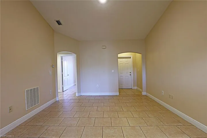 Unfurnished room featuring arched walkways and light tile patterned floors