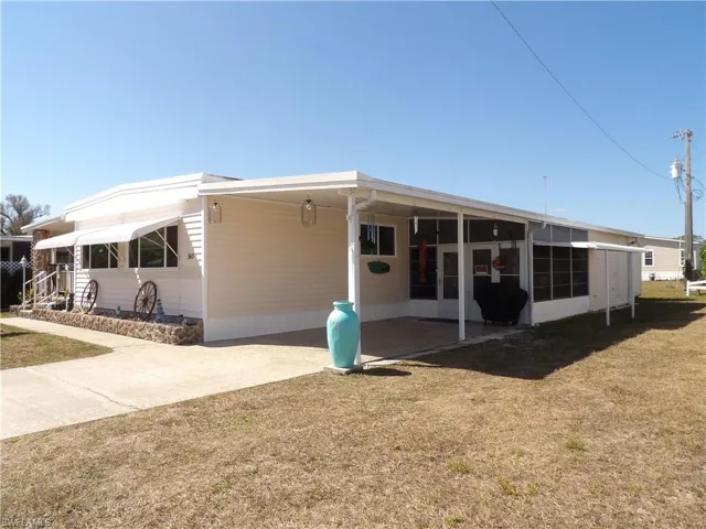 View of front of property with an attached carport, a front lawn, and driveway