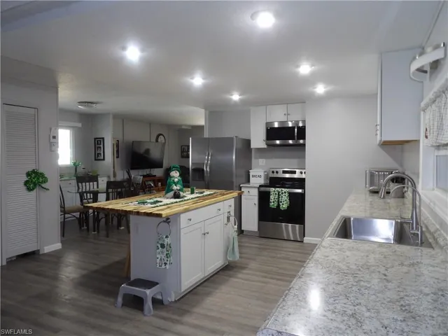Kitchen featuring stainless steel appliances, white cabinets, light wood-type flooring, butcher block counters, and a kitchen island
