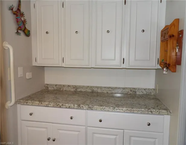 Kitchen featuring white cabinetry and light stone counters