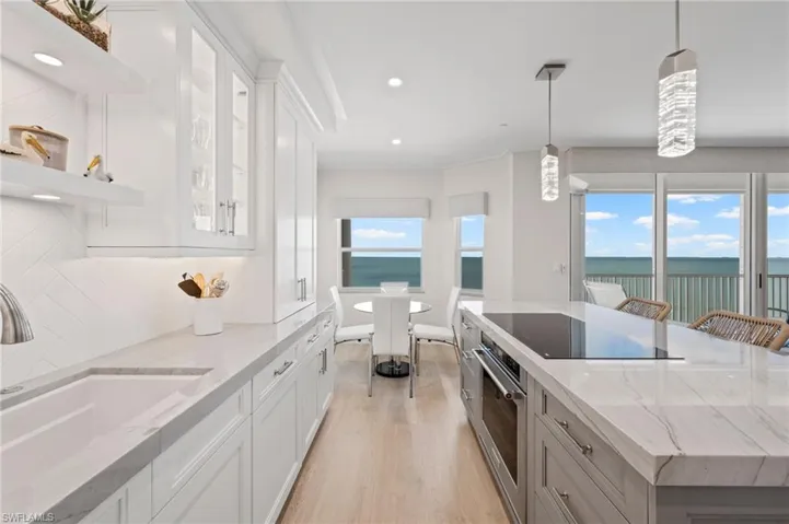 Kitchen with pendant lighting, stainless steel oven, white cabinets, a water view, and tasteful backsplash