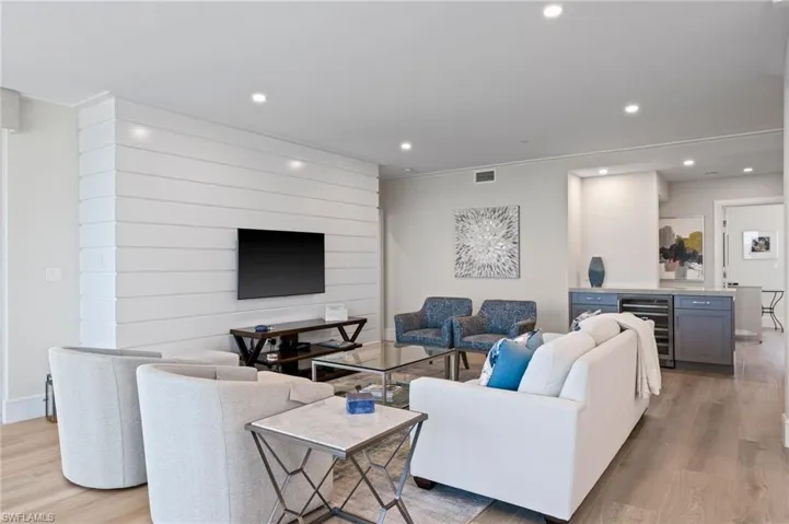 Living room featuring bar area, light wood-type flooring, wine cooler, and ornamental molding