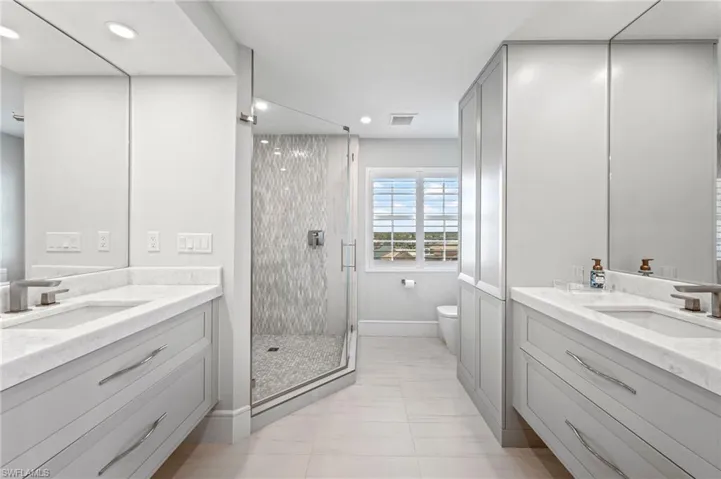 Bathroom with tile patterned flooring, vanity, a shower with shower door, and toilet