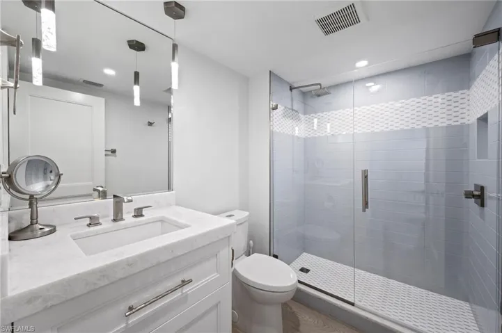 Bathroom with vanity, toilet, and a shower with shower door