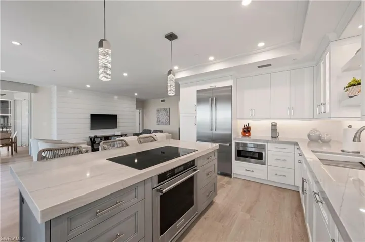 Kitchen featuring white cabinetry, a center island, stainless steel appliances, and light stone counters