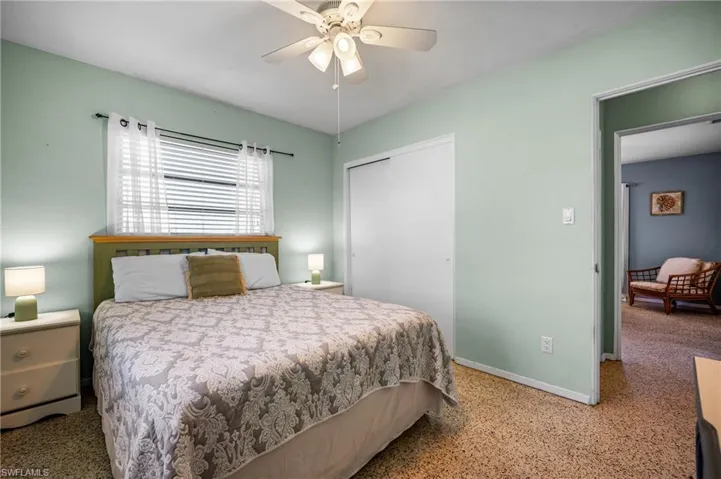 Bedroom featuring terrazzo flooring, a ceiling fan with integrated lighting, a sliding door closet, and a multi-pane window