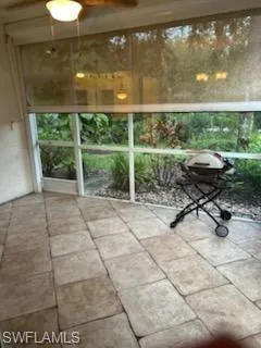Screened patio featuring large format tile flooring and a ceiling fan with integrated lighting