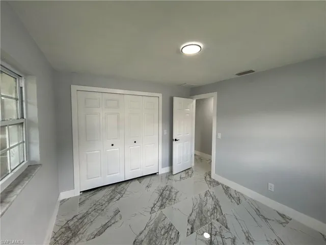 Unfurnished bedroom with a closet, multiple windows, and tile patterned floors