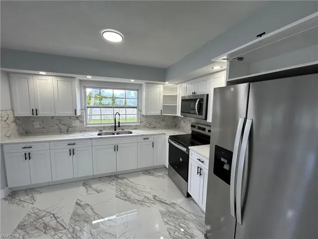 Kitchen featuring light tile patterned floors, sink, stainless steel appliances, and decorative backsplash