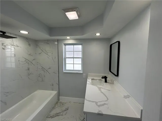 Bathroom featuring tiled shower / bath combo, tile patterned flooring, and vanity