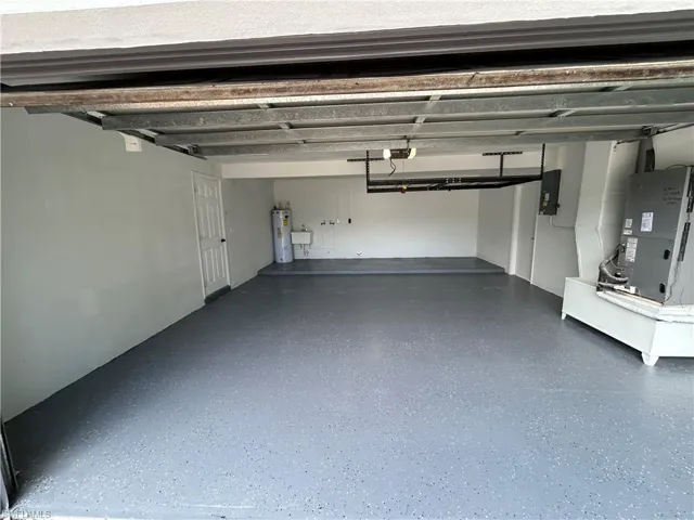 Garage with electric panel, a garage door opener, water heater, and heating unit