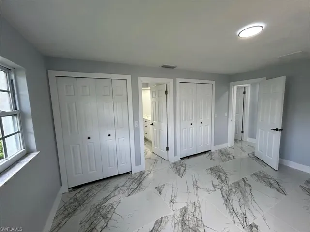Unfurnished bedroom featuring connected bathroom, multiple closets, and light tile patterned floors