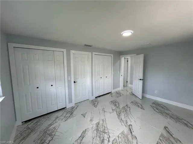 Unfurnished bedroom featuring light tile patterned floors and multiple closets
