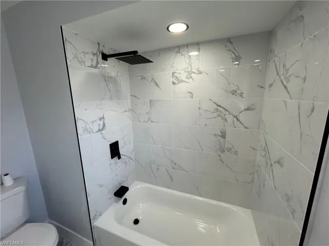 Bathroom with toilet and tiled shower / bath