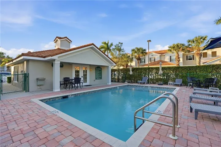 Community pool with a patio area, outdoor dining space, and a gate