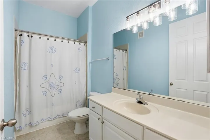 Full bath featuring vanity, shower / bath combo, and light tile patterned floors