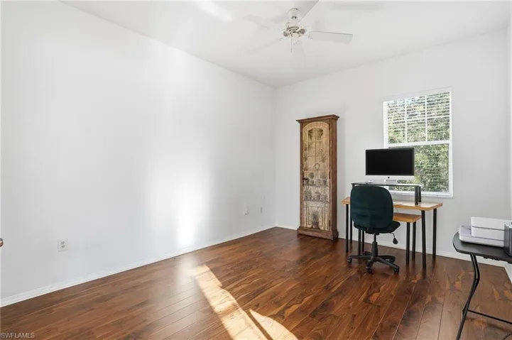 Home office with dark wood finished floors and a ceiling fan