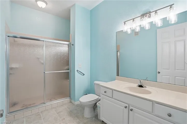 Bathroom with vanity, a shower stall, and a textured wall