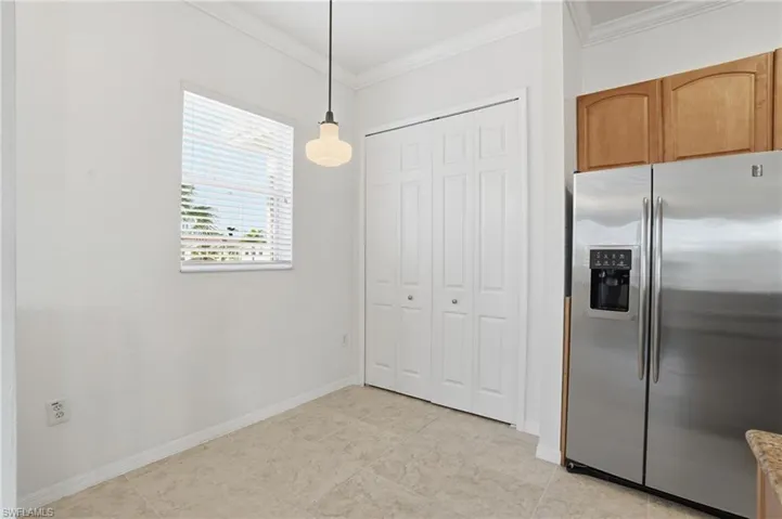 Kitchen with stainless steel fridge, crown molding, and decorative light fixtures