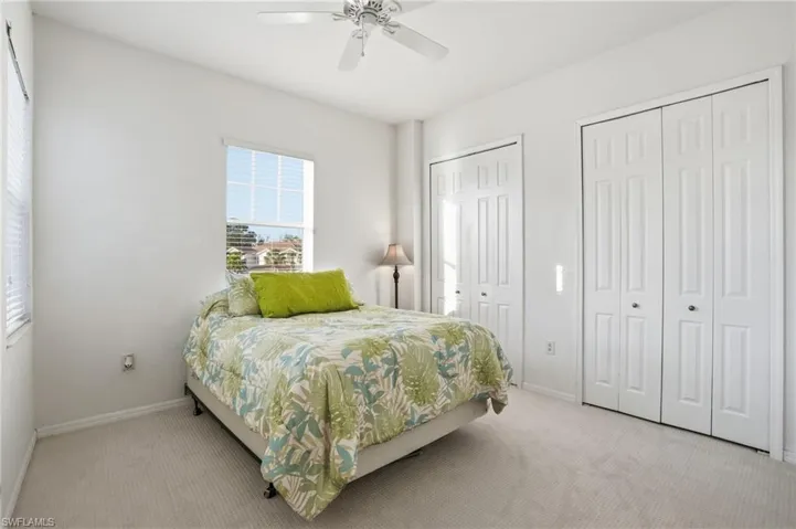 Carpeted bedroom with multiple closets and ceiling fan