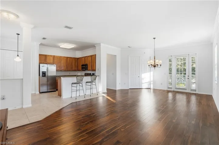 Unfurnished living room with ornamental molding, light wood-type flooring, and a chandelier