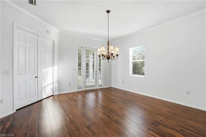 Unfurnished dining area featuring ornamental molding, dark wood finished floors, and a chandelier