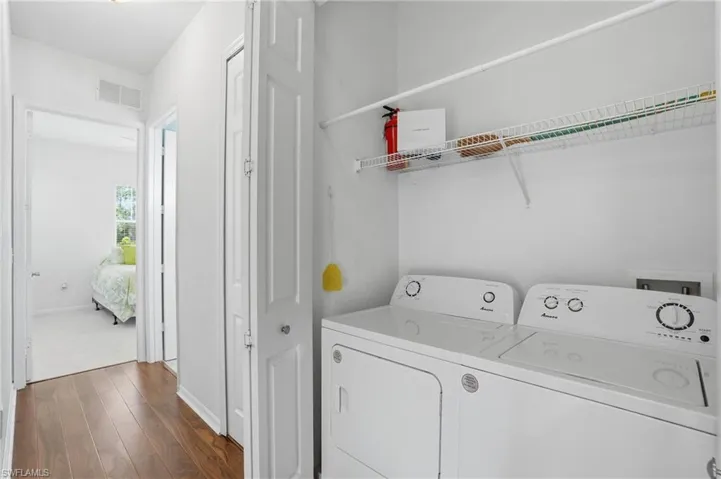 Laundry room featuring dark wood-type flooring and washing machine and dryer