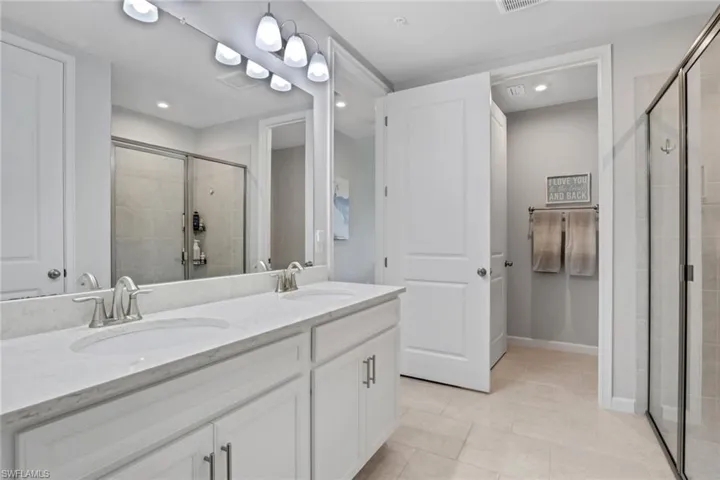 Full bathroom with double vanity, a shower stall, light tile patterned flooring, and recessed lighting
