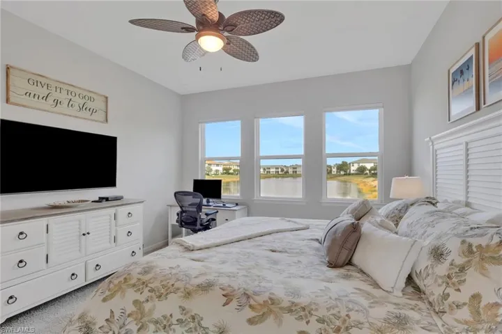 Bedroom featuring light colored carpet, ceiling fan, and a desk