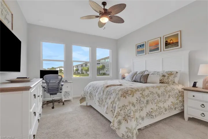 Bedroom with a desk, light colored carpet, and a ceiling fan