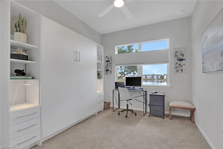 Office space with light carpet, a ceiling fan, and built in features