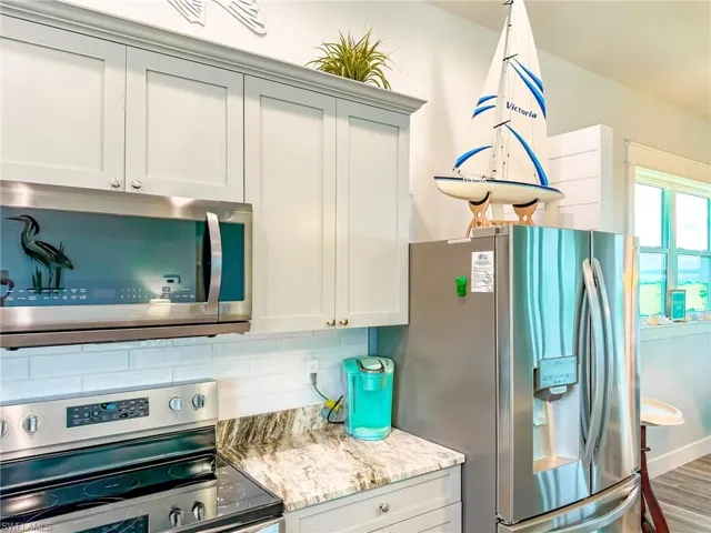 Kitchen featuring appliances with stainless steel finishes, light stone counters, recessed lighting, decorative backsplash, and light wood finished floors
