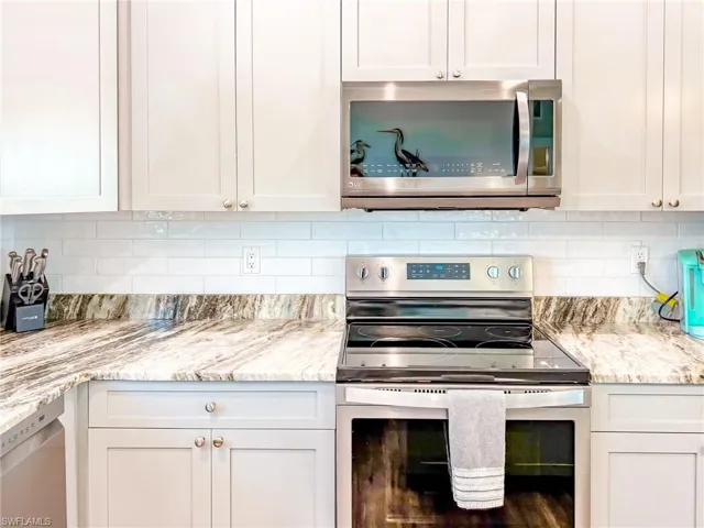 Kitchen with backsplash, dishwasher, light stone counters, and light wood-style flooring