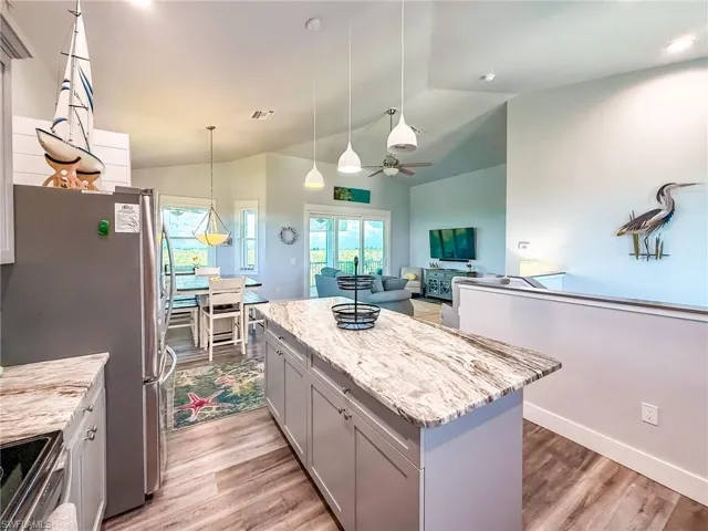 Kitchen with appliances with stainless steel finishes, light stone counters, backsplash, a center island, and decorative light fixtures