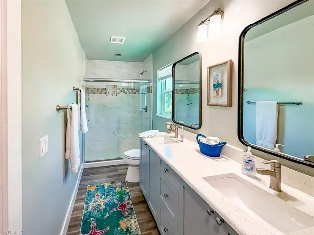 Full bath with a closet, double vanity, and light wood-style floors