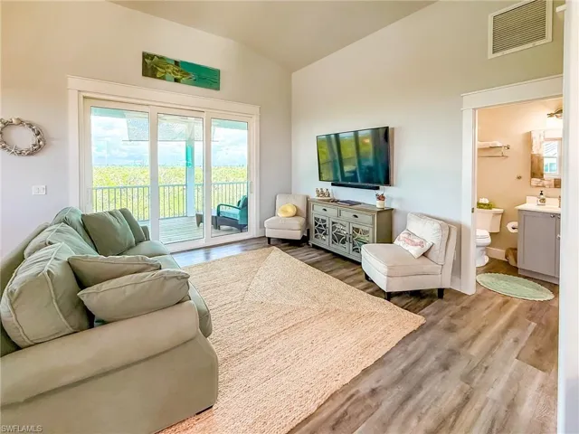 Living area featuring vaulted ceiling, dark wood-style floors, and a ceiling fan