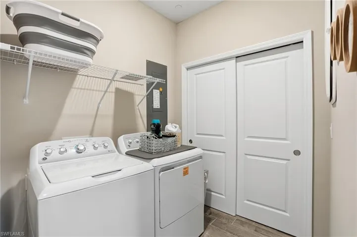 Laundry area featuring electric panel, wood finish floors, and washing machine and dryer