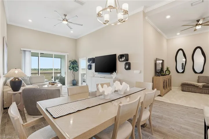 Dining area featuring ceiling fan, ornamental molding, recessed lighting, wood tiled floors, and a chandelier